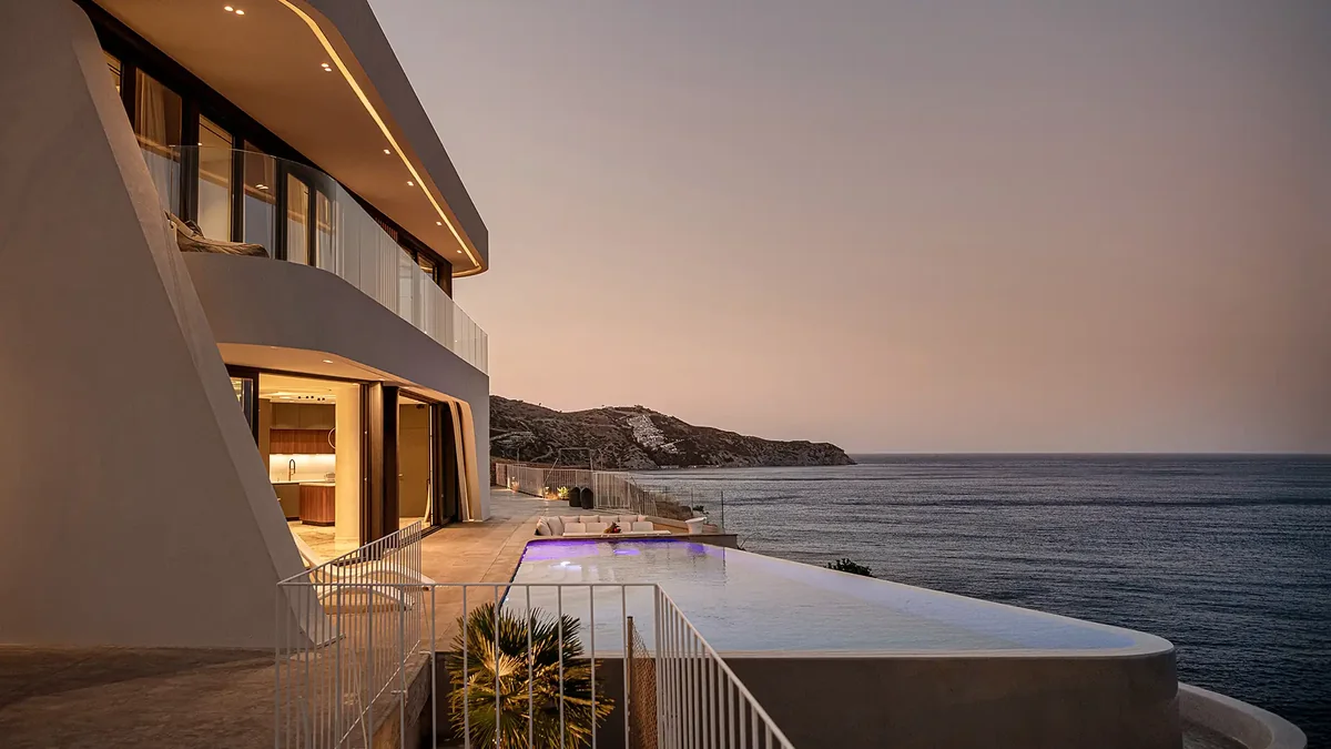 Meltemi Villa exterior at evening with illuminated pool terraces and Aegean view